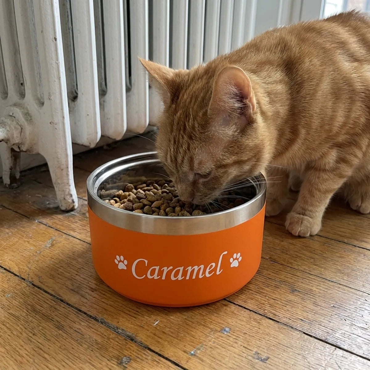 Gamelle inox orange avec prénom imprimé en blanc près d un radiateur